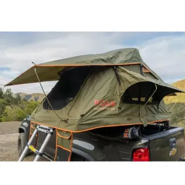 Roof top tent attached to a vehicle in a natural setting