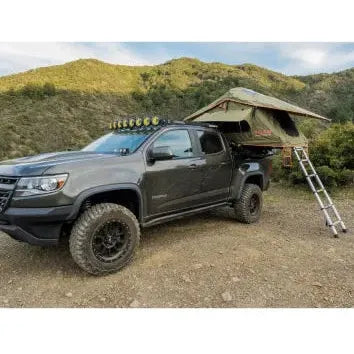 Black truck with a rooftop tent and ladder in a natural setting